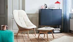 a living room with a chair and ottoman next to a cabinet in front of a window