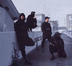 three young men sitting on the side of a building