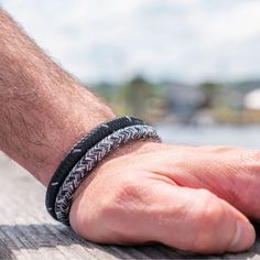 a man's hand with a black and white braided bracelet on his wrist