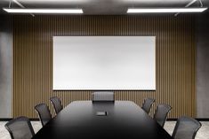 an empty conference room with black chairs and a large white board on the wall behind it