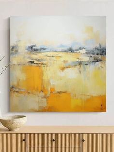 an abstract painting hangs on the wall above a dresser with a vase in front of it