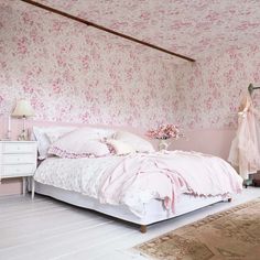 a bedroom with pink wallpaper and white furniture