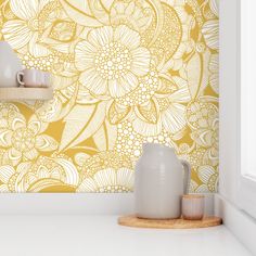 a yellow and white floral wallpaper with vases on the counter in front of it