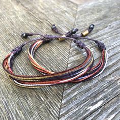 WOMENS WAXED CORD BRACELET: This hand-knotted multi-strand waxed cord bracelet includes two genuine Hematite stones and a Rumi Sumaq logo bead. In summer shades of muted violet purple, metallic gold, orange, brown and white it is the perfect beach accessory for surfers, sailors and beach lovers alike. Or you may think of this string bracelet as a sophisticated and grown up friendship bracelet. Buy one for yourself and another for your best friend. Or make it a sister's bracelet by purchasing one Adjustable Multi-strand Artisan Beaded Bracelets, Adjustable Multi-strand Jewelry For Beach, Earthy Style Bracelets With Sliding Knot For Beach, Earthy Beach Bracelets With Sliding Knot, Earthy Adjustable Bracelet With Sliding Knot, Earthy Sliding Knot Bracelets For The Beach, Earthy Adjustable Jewelry With Sliding Knot, Bohemian Hand-wrapped Waxed Cord Bracelet, Adjustable Bohemian Beaded Bracelets With Waxed Cord