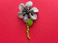 vintage 1960's enamel flower brooch / pin done with lacy white petals, a black and white dotted stamen and a green leafy stem finished with a rollover clasp. ✂ measurements ✂ 3" x  1.5" maker/label:   n/a condition:  very good.  no serious flaws or issues to note; sold as shown. Bridge City, White Petals, Floral Pins, Enamel Flower, Flower Pins, Flower Brooch, White Polka Dot, Brooch Pin, Polka Dot