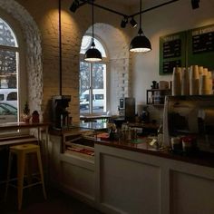 the interior of a coffee shop with tables and stools in front of large windows