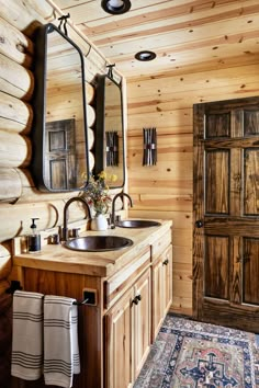 a bathroom with wooden walls and flooring, two sinks and mirrors on the wall