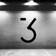 a black and white photo of the number three on a wall in a parking garage