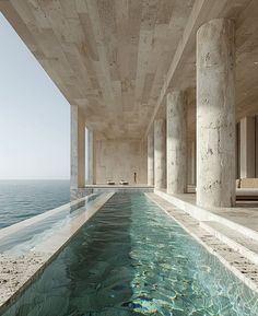 an indoor swimming pool in the middle of a large building with columns on both sides