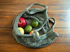 a knitted bag with apples and pears in it on a wooden table top