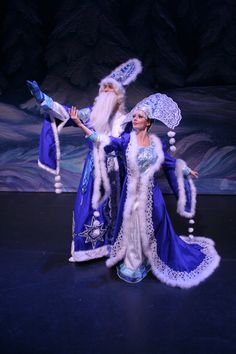 a woman dressed in blue and white is standing on stage with an evil man behind her