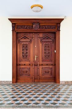 two wooden doors in an empty room with checkered floor