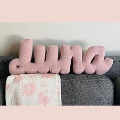 a pink stuffed animal sitting on top of a couch next to the word hello kitty