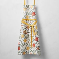 a white apron with yellow straps and fruit print on the front, hanging from a hook