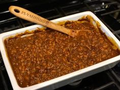 a casserole dish filled with baked beans and topped with a wooden spatula