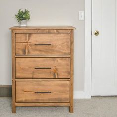 a wooden dresser sitting in front of a white door with a plant on top of it