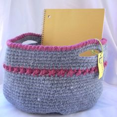 a crocheted basket with a notepad in the middle and a yellow tag hanging from it