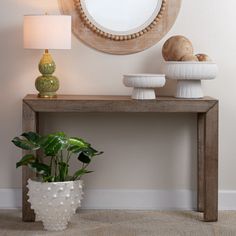 a table with a mirror, plant and lamp on it