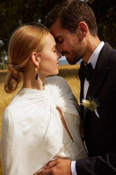 a man in a tuxedo kisses a woman's forehead as they stand close to each other