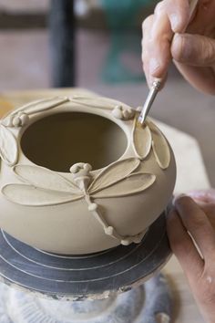 a person using a spoon to decorate a vase