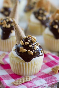 cupcakes with chocolate frosting and nuts on top, sitting on a checkered cloth