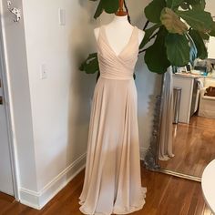 a dress is displayed on a mannequin in front of a mirror and plant