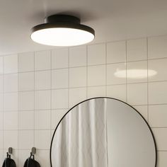 a bathroom with two black urinals and a round mirror