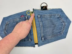 a hand is holding a pair of scissors in the back pocket of a jean jacket