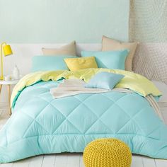 a bed with blue and yellow comforters in a room next to a white wall