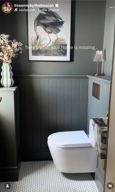 a white toilet sitting in a bathroom next to a painting