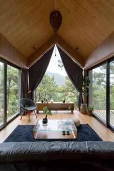 a living room with large windows and wooden ceiling