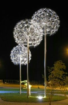 three tall metal sculptures with lights on them