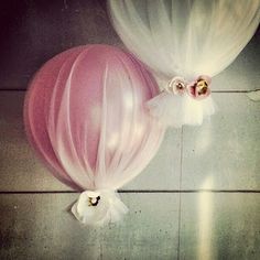 two balloons with white tulle and pink flowers on the top one has a large balloon attached to it's side