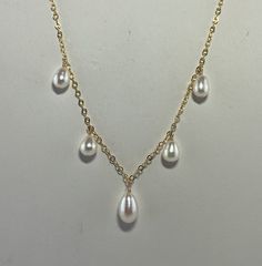 This is a freshwater pearl necklace with 5 teardrop shaped pearls dangling from an 18" gold-filled chain.  The pearls are white with a slight pink secondary color.  They measure 6-6.5mm in diameter and 9-11mm in length.  I've put the largest in the center with the smaller pearls graduating up on the sides.    The 1.7mm gold-filled, curb link chain is finished with a spring ring clasp.  This would be lovely as a wedding necklace or for any other occasion. This comes gift boxed and ships free USPS First Class.  If you'd like faster shipping you can upgrade to Priority Shipping at checkout for $5.50. Thank you for viewing. White Teardrop Pearl Necklace In Dainty Style, Dainty White Teardrop Pearl Necklace, Pearl Teardrop Drop Necklace With Pearl Charm, Teardrop Pearl Drop Necklace, Gold Teardrop Pearl Chain Drop Necklace, Gold Teardrop Pearl Drop Necklace, Gold Teardrop Pearl Necklace, Gold Dangle Necklace With Pearl Drop, Gold Drop Necklace With Pearl Dangle