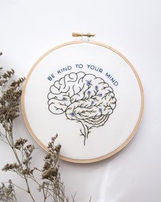 a cross stitch pattern with the words, be kind to your mind on it next to some dried flowers