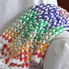 a crocheted blanket sitting on top of a white couch