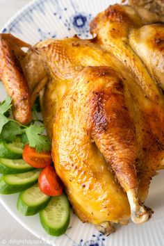 a close up of a chicken on a plate with veggies and cucumbers