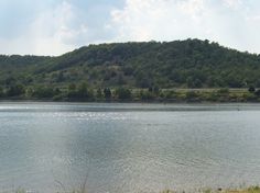 a large body of water sitting next to a lush green hillside