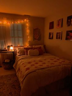 a bed in a bedroom with lights on the wall and pictures hanging up above it