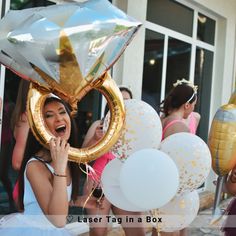 a woman is holding balloons in front of her face