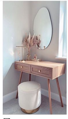 a vanity with a mirror, stool and plant in the corner on top of it