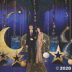 a man and woman standing in front of a stage set with stars and moon decorations