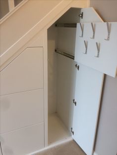 an empty closet under the stairs in a room with white walls and carpeted flooring