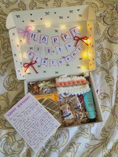 a birthday gift box with writing and lights on the top is sitting on a bed