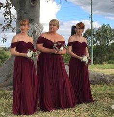 three bridesmaids standing in front of a grave with their dresses pulled back and flowers in their hair