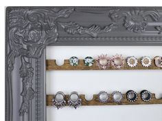 there are several pairs of rings on the wall in front of a mirror that is decorated with flowers and leaves