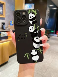 a woman holding up a phone case with pandas on it in front of a counter