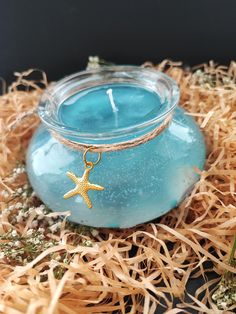 a blue jar with a starfish charm sitting on top of some sea grass and straw