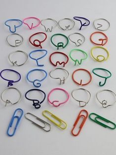 a bunch of different colored paper clips on a white surface with scissors in the middle