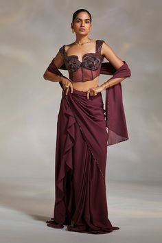 Wine georgette pre-draped saree with ruffle detailing and a side slit. Paired with a corset padded blouse.
Component: 2
Pattern: Embroidery
Type Of Work: Beads
Neckline: Notched
Sleeve Type: Sleeveless
Fabric: Corset: Satin and Lycra Mesh; Saree: Georgette
Color: Wine
Other Details: 
Beads embroidery
Notched neckline
Attached lining
Approx weight (in kg) : 1.2
Occasion: Destination Wedding - Aza Fashions Saree With Corset, Crystal Blouse, Drape Sari, Ruffle Sarees, Saree Georgette, Corset Blouse, Ruffle Saree, Padded Blouse, Drape Saree